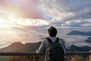 jonge man reizigers kijken naar de zonsopgang en de zee van mist op de berg in de ochtend, reizen lifestyle concept foto