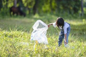 Aziatische kinderen doen vrijwillig plastic flessen in vuilniszakken. vrijwilligersconcept en ecologie foto