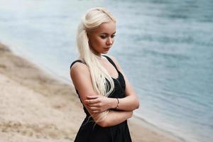 mooie vrouw in zwarte jurk op het strand foto
