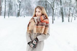 jong mooi meisje in winterkleren op een vintage achtergrond van het park foto