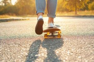 skateboarden benen in skatepark. prachtig weer met de zonsondergang. vrouw gaat vooruit foto