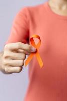 oranje lint voor leukemie, nierkankerdag, wereld multiple sclerose, crps, zelfverwondingsmaand. gezondheidszorg en woord kanker dag concept foto