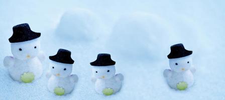 witte sneeuwpop in een zwarte hoed in de sneeuw. foto
