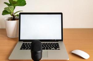 leeg scherm van laptopcomputer met microfoon en viool vijgenboompot op houten tafel foto