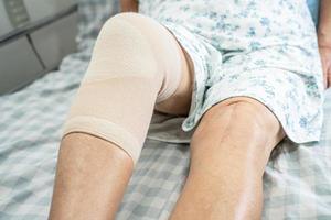 Aziatische senior of oudere oude dame vrouw patiënt met knie ondersteuning pijn gezamenlijke op bed in verpleegafdeling ziekenhuis, gezond sterk medisch concept. foto