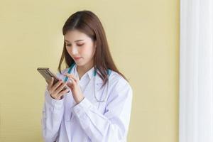Aziatische vrouwelijke arts die een mobiele telefoon gebruikt foto