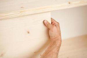 hand houten plank op zijn plaats plaatsen foto