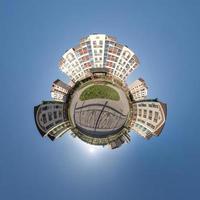 kleine planeet in blauwe lucht met wolken in het centrum in de buurt van moderne wolkenkrabbers of kantoorgebouwen. transformatie van bolvormig 360 panorama in abstracte luchtfoto. foto