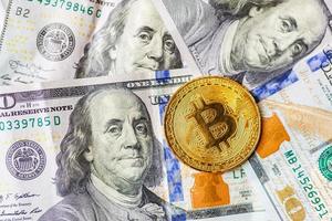 virtueel geld gouden bitcoin op honderd dollar rekeningen achtergrond. wissel bitcoin contant in voor een dollar. foto