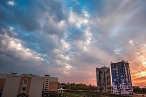 's avonds pluizige krullende rollende wolken van geweldige zonsondergang tegen de achtergrond van flatgebouwen met meerdere verdiepingen foto