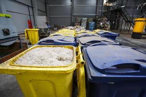 containers met versnipperd plastic voorbereid voor verdere verwerking omsmelten en recyclen met shredder en balen plastic afval op de achtergrond. moderne fabriek voor het verwerken en sorteren van afval foto