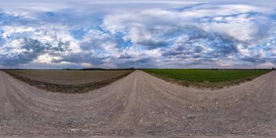 volledig naadloos bolvormig hdri-panorama 360 graden hoekzicht op onverharde weg tussen velden in de lente met onweerswolken voor regen in equirectangular projectie, klaar voor vr ar-inhoud foto