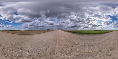 volledig naadloos bolvormig hdri-panorama 360 graden hoekzicht op onverharde weg tussen velden in de lente met onweerswolken voor regen in equirectangular projectie, klaar voor vr ar-inhoud foto