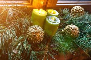 kerstkaarsen ballen en sparren takken op houten vensterbank. Feestelijke stemming foto