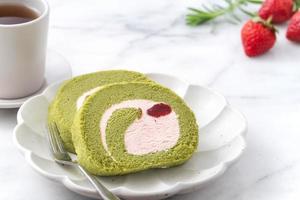 heerlijke matcha swiss roll cake plakjes met aardbeienroom op witte achtergrond. foto