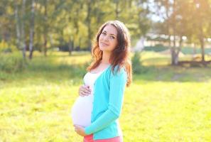 vrij lachende zwangere vrouw in zonnige zomerdag foto