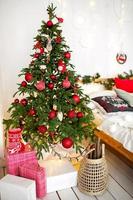 versierde kerstboom in de woonkamer met bank, deken, lichtslingers. slaapkamer met een bed. nieuwjaar, kerstmis foto