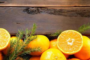 verse mandarijnen in bruine doos op houten achtergrond met groene dennentakken. frame, kopieer ruimte, vakantie en wintergeur, nieuwjaar, kerstmis. gezonde voeding, jus d'orange, etalage. snijden en snijden foto