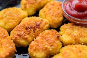 gefrituurde krokante kipnuggets met ketchup op zwarte plaat foto