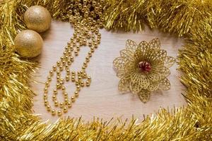 kerst nieuwjaar vakantie achtergrond. gouden klatergoud, bloem, slinger en ballen op houten achtergrond foto