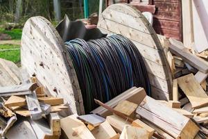 houten spoel van elektrische kabel tussen houten stammen op de binnenplaats foto