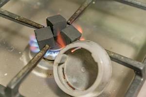 voorbereiding van zelfgemaakte waterpijp. verwarming van kolen op een gasfornuis foto