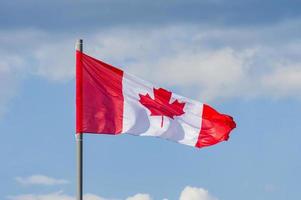 de nationale vlag van canada wappert over de blauwe lucht foto