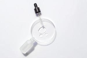 cosmetische pipet serum op een petrischaal op witte achtergrond. cosmetologie en farmaceutica concept. zure peeling, gezichtsolie, collageen foto