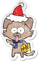 verontruste sticker cartoon van een hond met een kerstcadeau met een kerstmuts vector