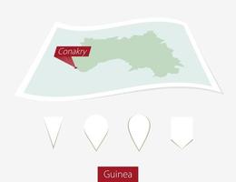 gebogen papier kaart van Guinea met hoofdstad conakry Aan grijs achtergrond. vier verschillend kaart pin set. vector