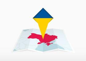 Oekraïne is afgebeeld Aan een gevouwen papier kaart en vastgemaakt plaats markeerstift met vlag van Oekraïne. vector
