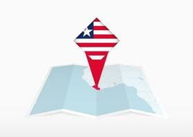 Liberia is afgebeeld Aan een gevouwen papier kaart en vastgemaakt plaats markeerstift met vlag van Liberia. vector