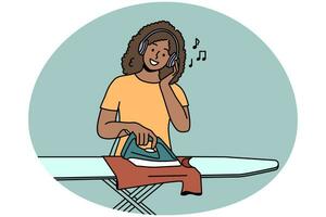 glimlachen jong vrouw in hoofdtelefoons strijken kleren Bij huis. gelukkig Afrikaanse Amerikaans meisje luister naar muziek- in oortelefoons Doen huis klusjes. vector illustratie.