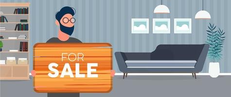 een man met een bril houdt een houten bord vast met het opschrift te koop. jonge man met een houten bord. het concept van de verkoop van een appartement, kantoor of gebouw. vector. vector