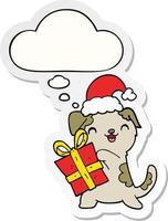 schattige cartoon puppy met kerstcadeau en hoed en gedachte bel als een gedrukte sticker vector