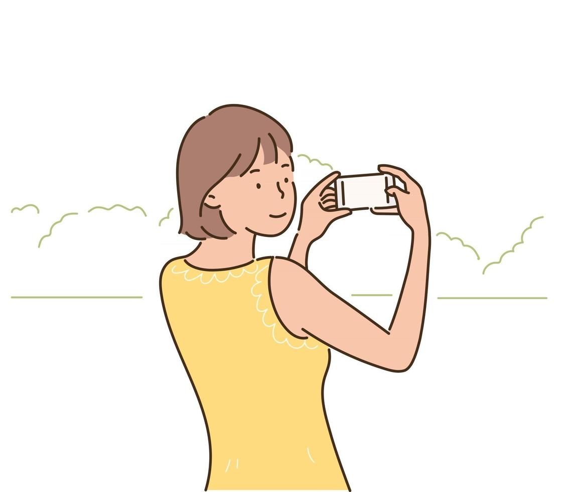 en kvinna håller en kamera och tar bilder av ett landskap. handritade illustrationer för stilvektordesign. vektor