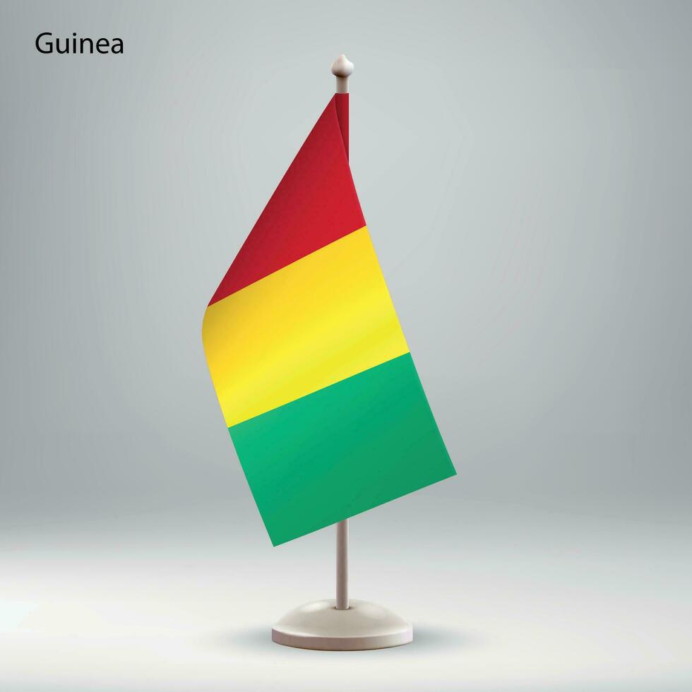 flagga av guinea hängande på en flagga stå. vektor