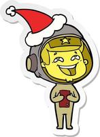 klistermärke tecknad av en skrattande astronaut som bär tomtehatt vektor