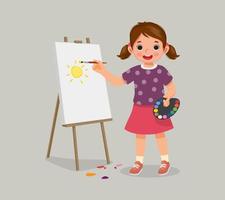 glad liten flicka konstnär håller färgpalett och penselmålning på duken vektor