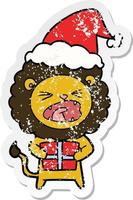 beunruhigter Aufkleber-Cartoon eines Löwen mit Weihnachtsgeschenk, das Sankt-Hut trägt vektor
