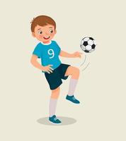 söt liten pojke spelar fotboll praktiserande sparkar de fotboll med hans knä vektor