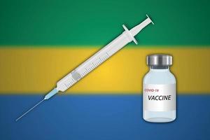 Spritze und Impfstofffläschchen auf unscharfem Hintergrund mit Gabun-Flagge, vektor