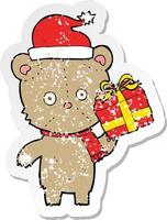 retro nödställda klistermärke av en tecknad jul nallebjörn med present vektor