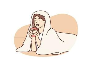 Mädchen mit Tasse von heiß Kaffee Lügen eingewickelt im Decke und lächelt genießen Winter Morgen. Frau Trinken heiß trinken mit Decke zu behalten warm nach Gehen auf kalt Straße zum Herbst Stimmung Konzept vektor