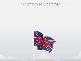 Storbritanniens flagga vajar på en stolpe som står högt under den vita himlen vektor