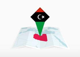 Libyen ist abgebildet auf ein gefaltet Papier Karte und festgesteckt Ort Marker mit Flagge von Libyen. vektor