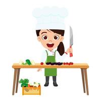 glückliche süße Kindermädchen Kochfigur mit Kochoutfit, die auf dem Tisch steht und Gemüse schneidet vektor