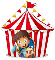 En ung pojke med en biljett och en popcorn nära tältet vektor