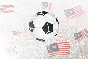 National Fußball Mannschaft von Malaysia erzielte Ziel. Ball im Tor Netz, während Fußball Unterstützer sind winken das Malaysia Flagge im das Hintergrund. vektor