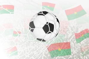 nationell fotboll team av Burkina faso gjorde mål mål. boll i mål netto, medan fotboll supportrar är vinka de Burkina faso flagga i de bakgrund. vektor